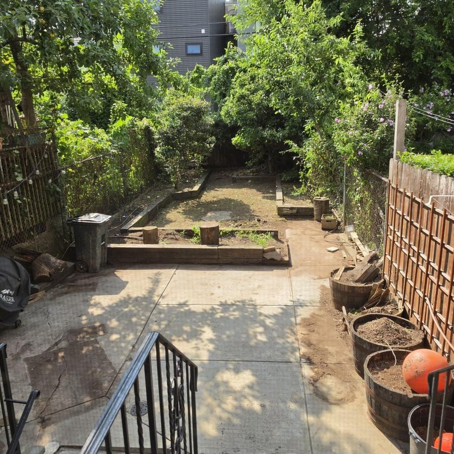 A cleared and swept backyard patio, weeds and debris removed